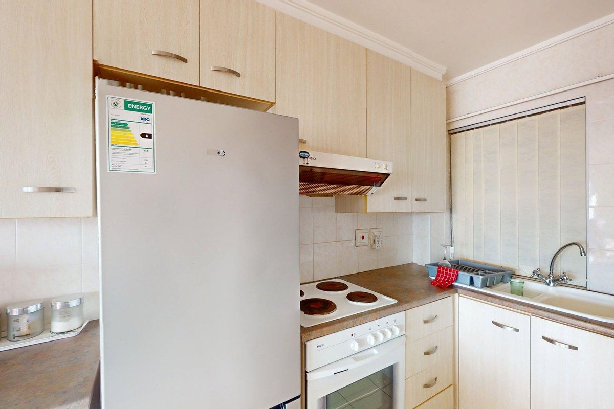 Functional kitchen featuring light wood-tone cabinetry, laminate countertops, a built-in electric stove with extractor fan, and a double bowl sink with tiled backsplash.