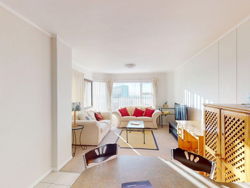 Open-plan living and dining area featuring neutral walls, a mix of carpet and tile flooring, and large windows providing natural light.