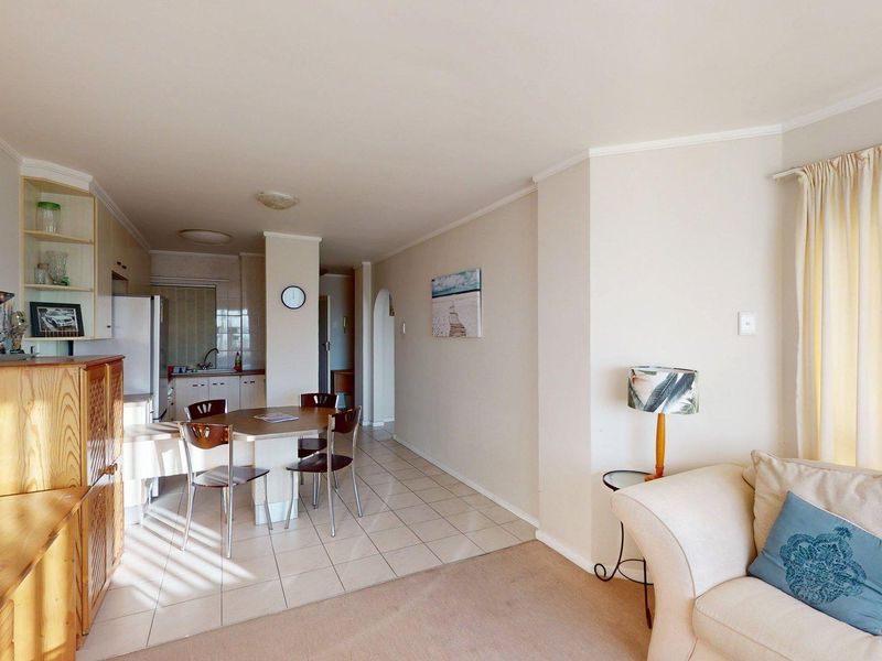 Open-plan living and dining area featuring tiled kitchen flooring, carpeted lounge space, and neutral wall finishes.