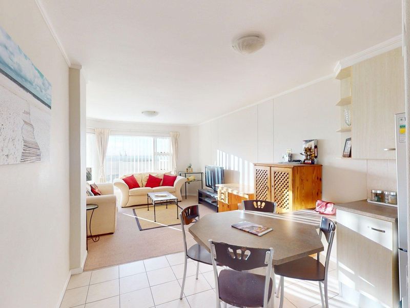 Open plan living and dining area featuring tiled kitchen flooring, carpeted lounge space, and neutral wall finishes.