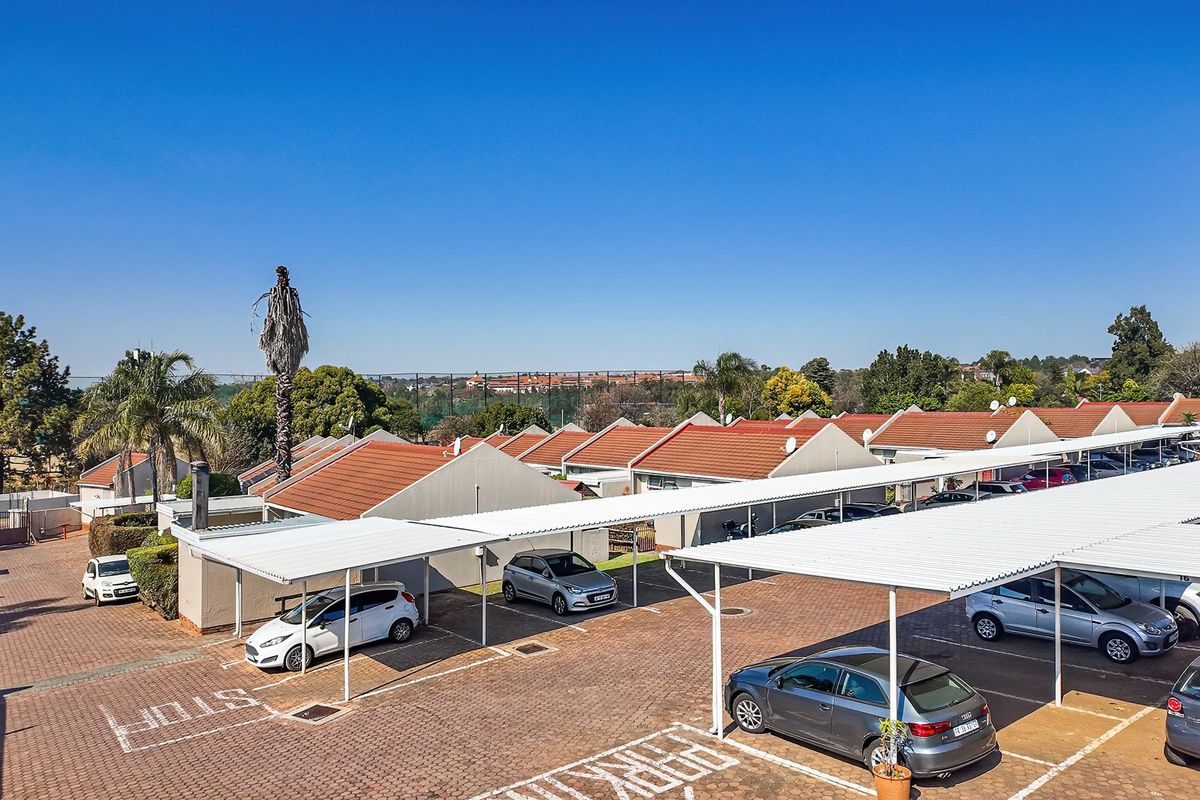 Aerial view of a townhouse complex featuring paved driveways and covered carport parking bays for residents.