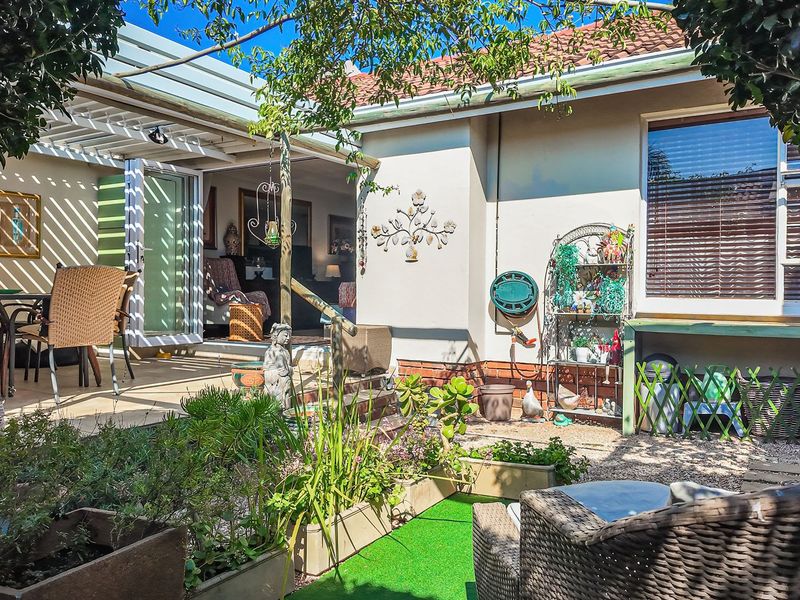 A rear exterior view of the townhouse featuring a covered patio area with tiled flooring, pergola structure, and access to the interior living space.