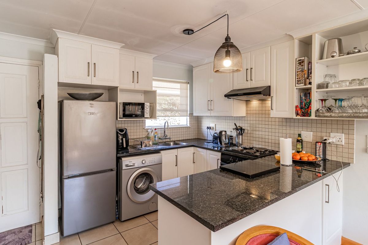 A functional kitchen featuring granite countertops, white cabinetry, a tiled backsplash, and integrated appliances, offering a clean and practical workspace.