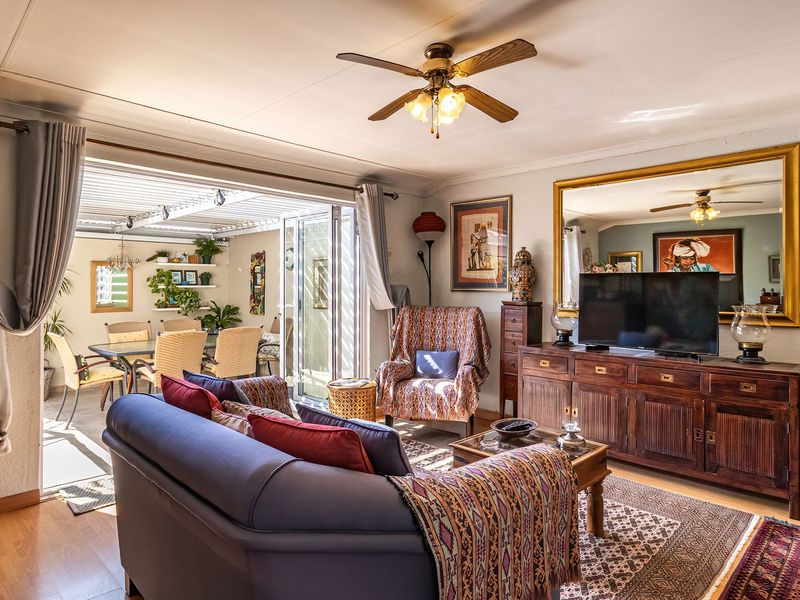 Open plan living area featuring laminate flooring and a ceiling fan, with seamless flow to a covered patio through large sliding glass doors.