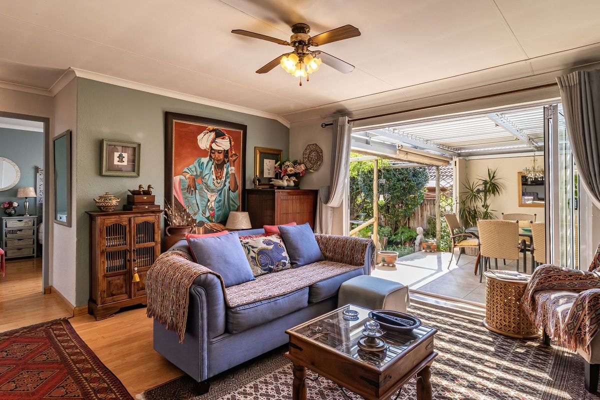 A comfortable living room featuring laminate flooring and a ceiling fan, with large sliding doors providing seamless access to a covered outdoor patio area.