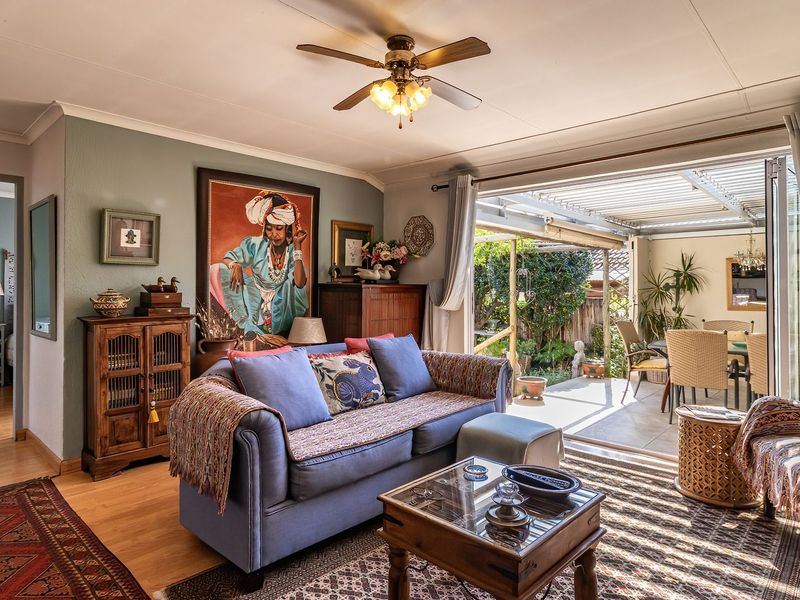 A comfortable living room featuring laminate flooring and a ceiling fan, with large sliding doors providing seamless access to a covered outdoor patio area.