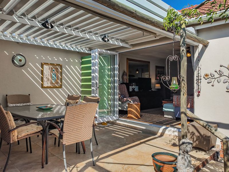A covered outdoor patio featuring a louvred pergola, tiled flooring, and bi-fold doors providing seamless access to the interior living space.