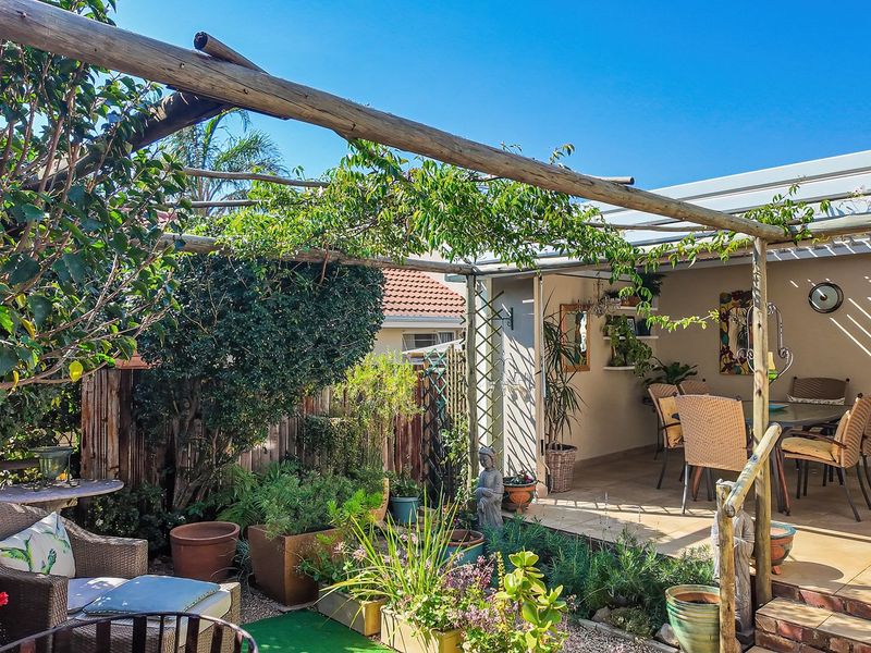 A covered patio area featuring a rustic timber pergola, tiled flooring, and direct access to a landscaped garden space.
