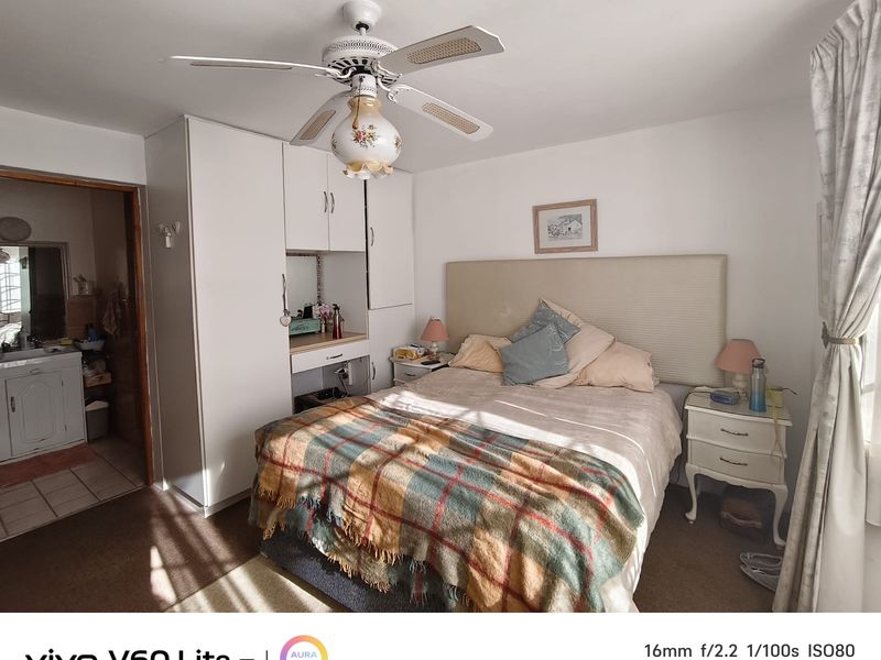 A bedroom featuring built-in cabinetry with an integrated vanity, a ceiling fan, and carpeted flooring, with an adjoining bathroom visible.