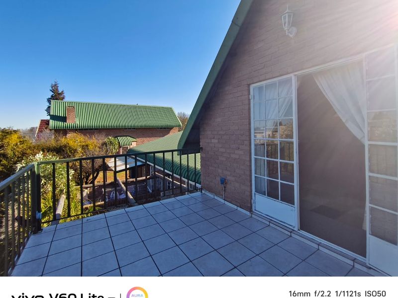 An elevated balcony featuring tiled flooring, a metal balustrade, and direct access to the interior through classic french doors.