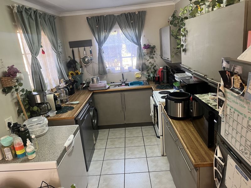 A functional kitchen featuring tiled flooring, laminate countertops, and built-in cabinetry with a double sink and electric stove.