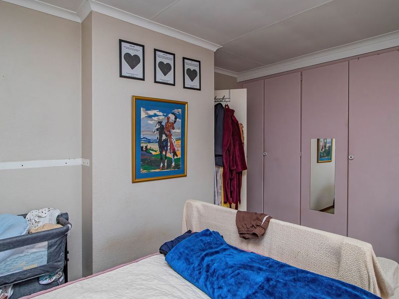 A bedroom featuring built-in cupboards and coved ceiling detailing, offering a functional space with potential for cosmetic updates.