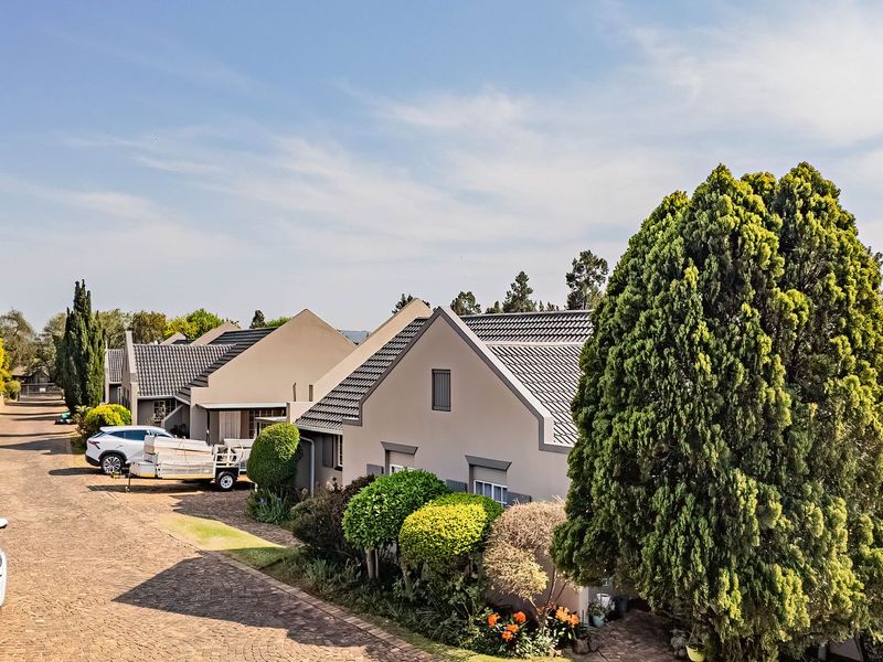 A view of the townhouse complex exterior featuring tiled roofs, paved driveways, and established garden landscaping.