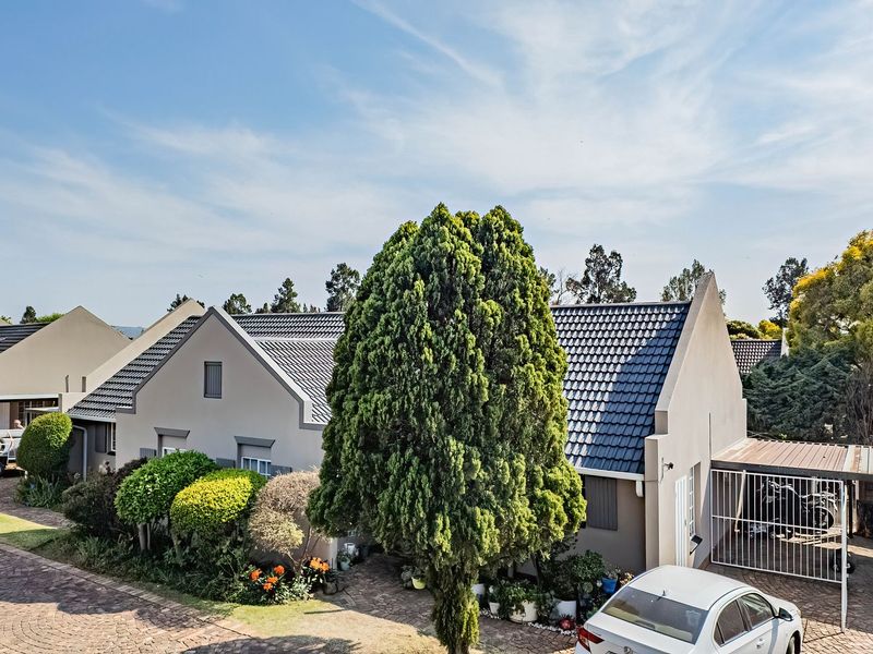 Front exterior view of the townhouse featuring a tiled roof, paved driveway, and a covered carport area.