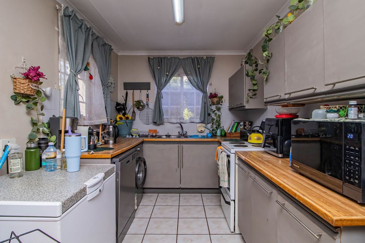 Functional kitchen featuring built-in cabinetry, wooden countertops, a stainless steel sink, and tiled flooring, offering a practical layout for daily meal preparation.