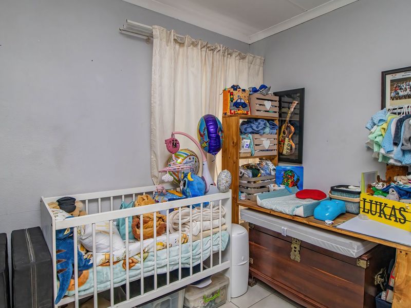 A bedroom featuring tiled flooring, a built-in cupboard, and a curtain rail, currently utilized as a nursery.