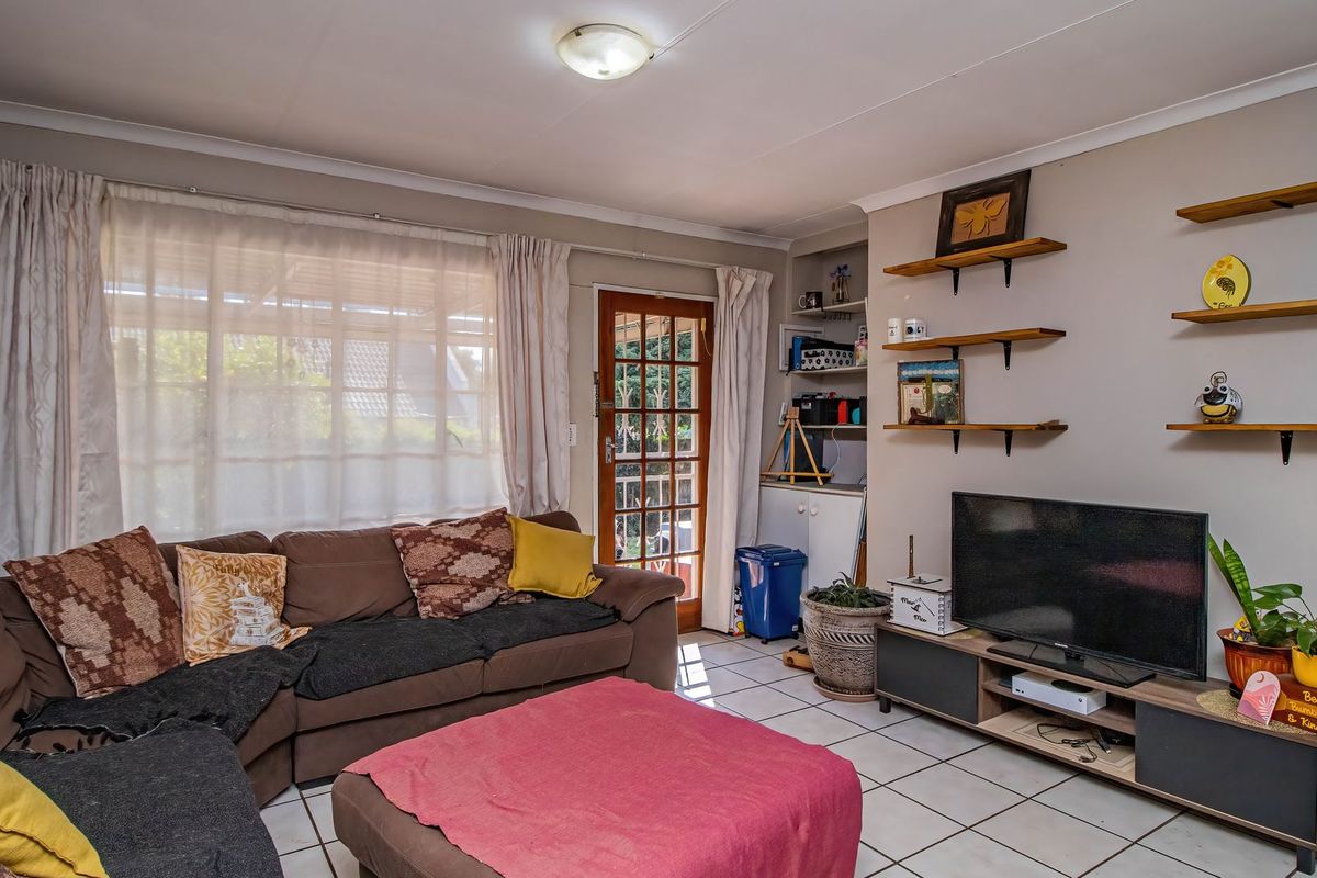 A comfortable living room featuring tiled flooring, built-in shelving, and a glass panel door providing access to the outdoor area.