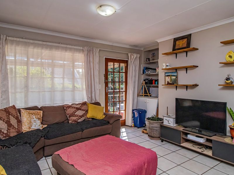 A comfortable living room featuring tiled flooring, built-in shelving, and a glass panel door providing access to the outdoor area.