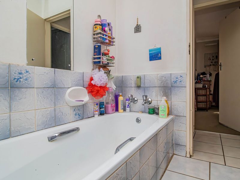 A functional bathroom featuring a bathtub with tiled surround and flooring, offering a dated aesthetic ready for modernization.