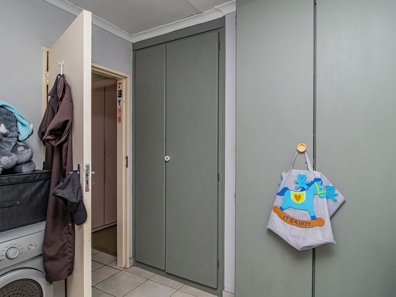 A functional laundry area featuring built-in storage cupboards and tiled flooring, providing practical utility space within the home.