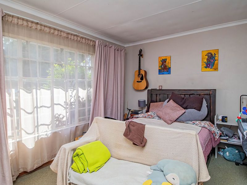 A bedroom featuring a large window with natural light and coved ceiling details, providing a comfortable space for rest.
