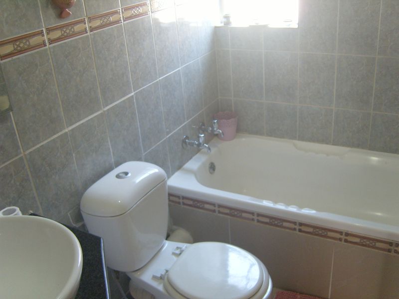 A functional bathroom featuring a bathtub, toilet, and basin with tiled walls and a vanity countertop.