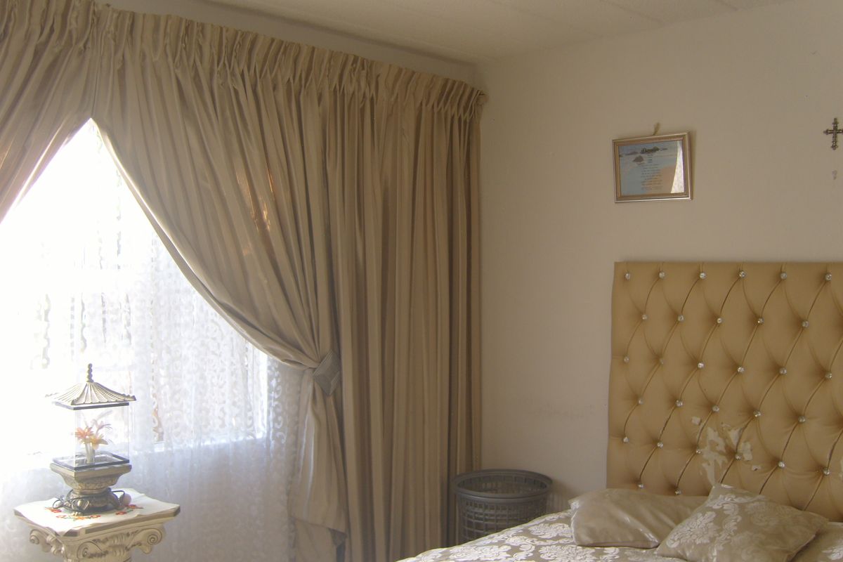 A bedroom featuring a textured ceiling and full-length curtains, providing a neutral base for potential interior updates.