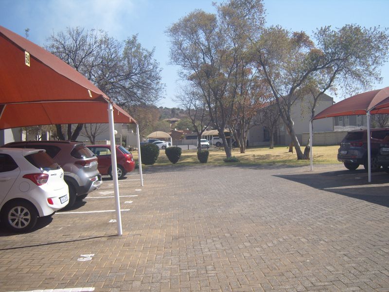 Outdoor parking area featuring paved surfaces and covered shade cloth carports for resident vehicles.