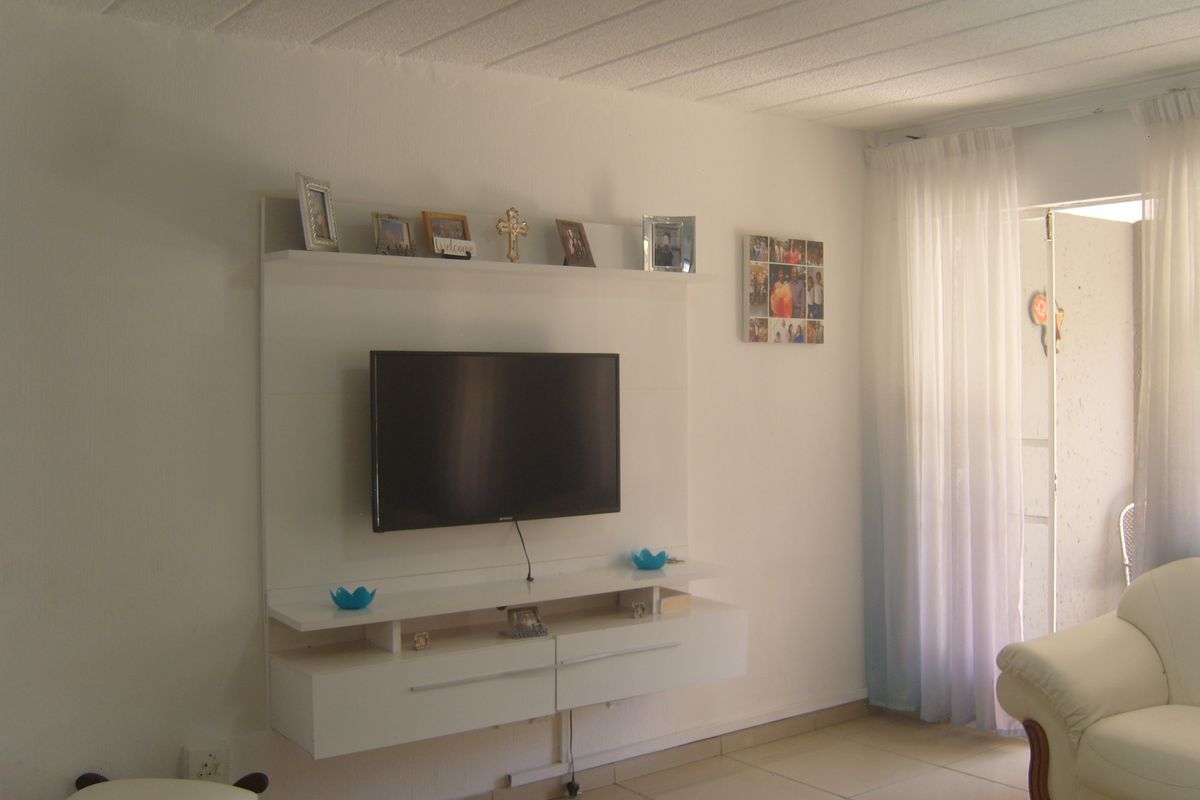 A living room featuring a white built-in media console, tiled flooring, and a sliding glass door leading to an outdoor area.