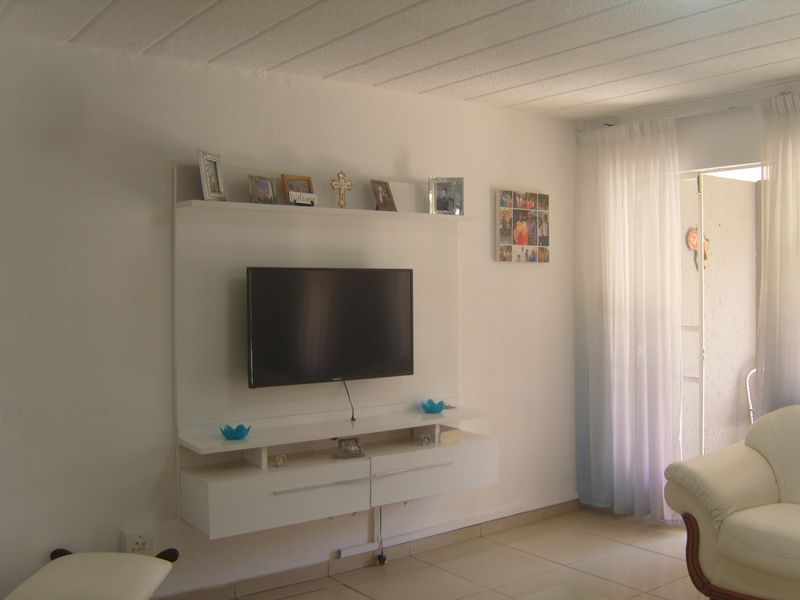 A living room featuring a white built-in media console, tiled flooring, and a sliding glass door leading to an outdoor area.