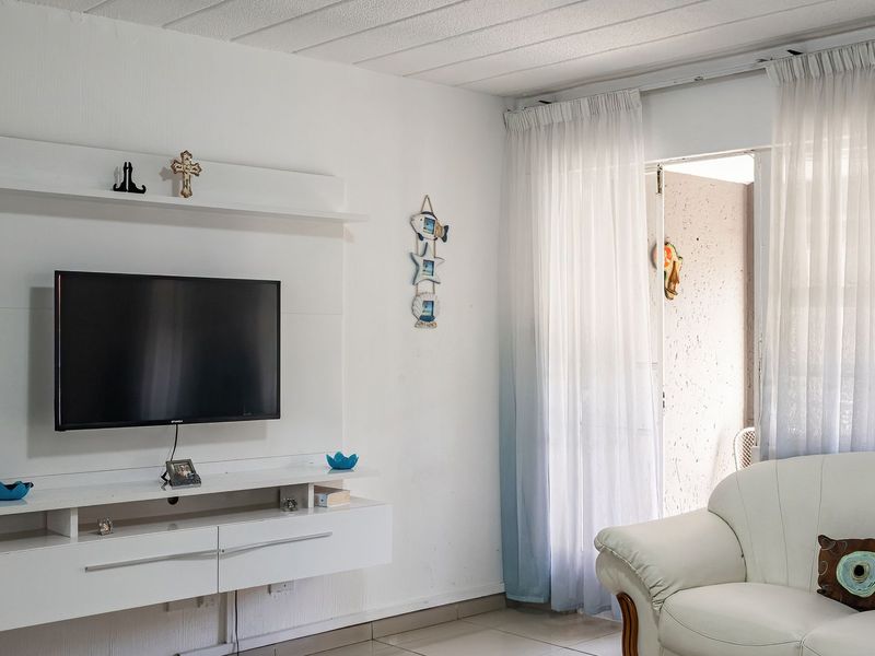 Living room featuring a built-in media console, tiled flooring, and direct access to an outdoor area through a sliding glass door.