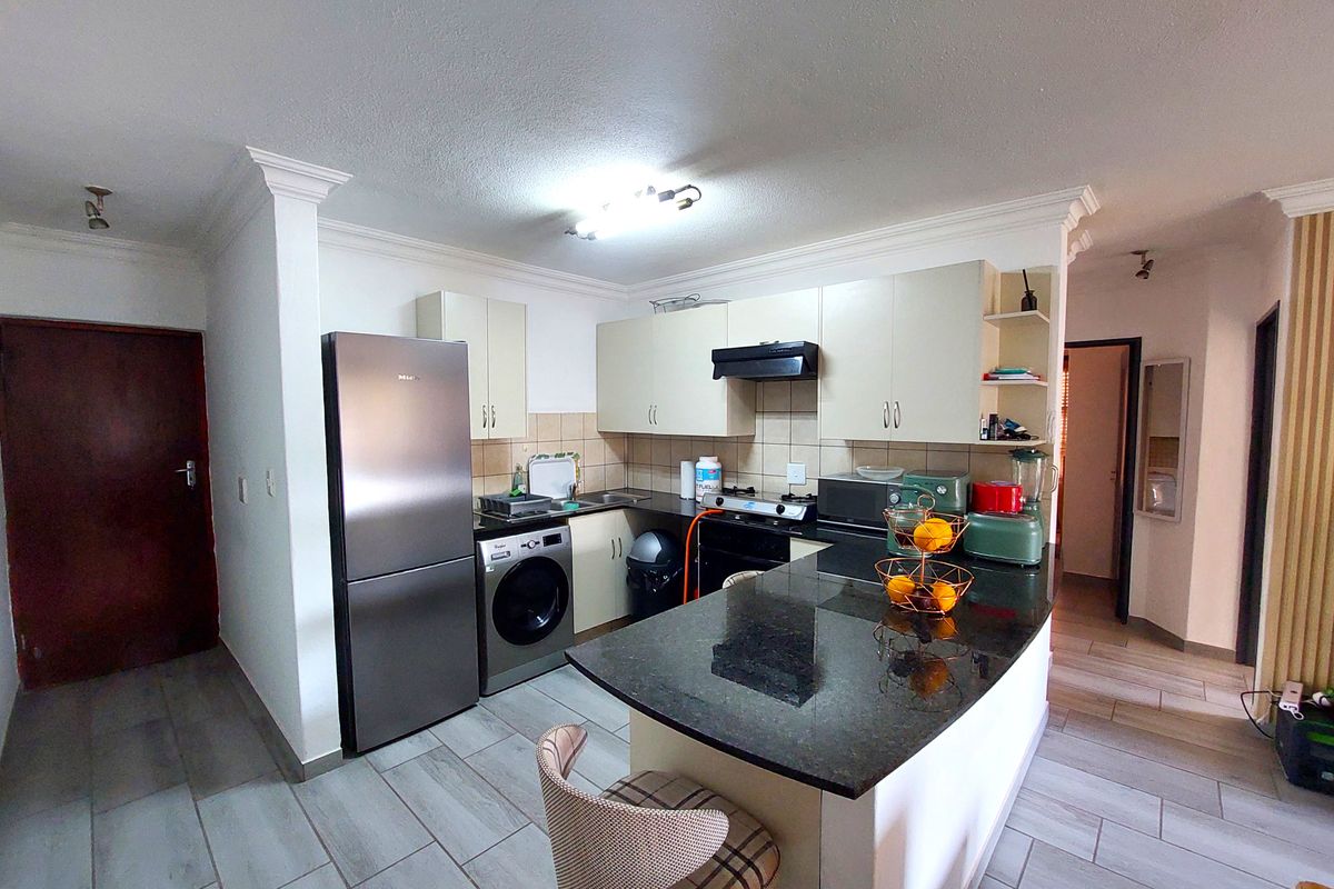 A functional kitchen featuring granite countertops, built-in cabinetry, an integrated breakfast bar, and tiled flooring, offering a practical layout for daily use.
