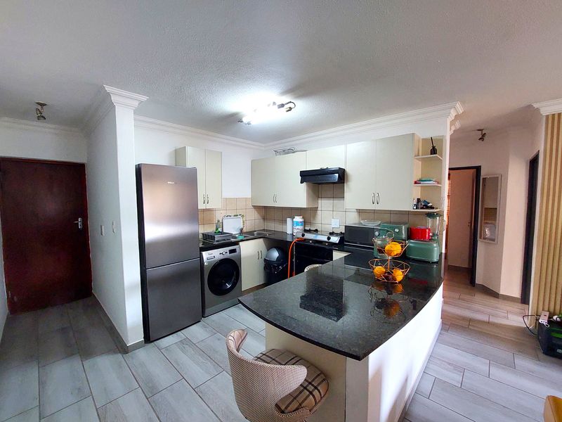 A functional kitchen featuring granite countertops, built-in cabinetry, an integrated breakfast bar, and tiled flooring, offering a practical layout for daily use.
