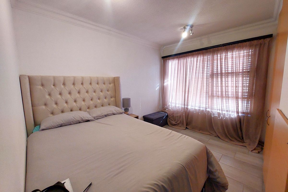 A bedroom featuring tiled flooring, built-in wardrobe storage, and ceiling cornice detailing, providing a functional and neutral living space.