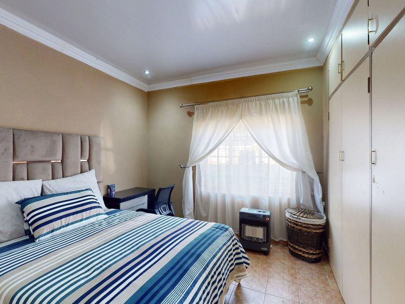 A functional bedroom featuring built-in cupboards, tiled flooring, and recessed downlights, offering a neutral base for personalization.