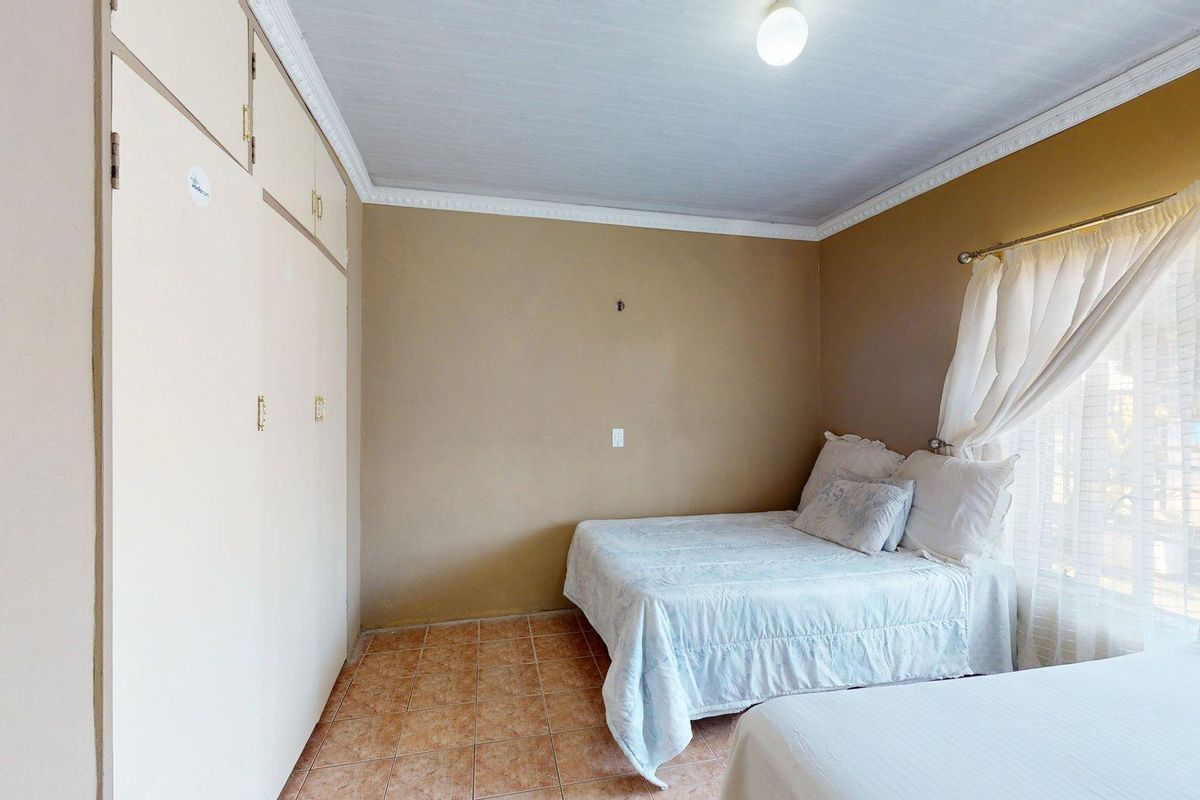 A bedroom featuring tiled flooring, built-in cupboards, and decorative ceiling cornicing, offering a functional space with potential for cosmetic updates.