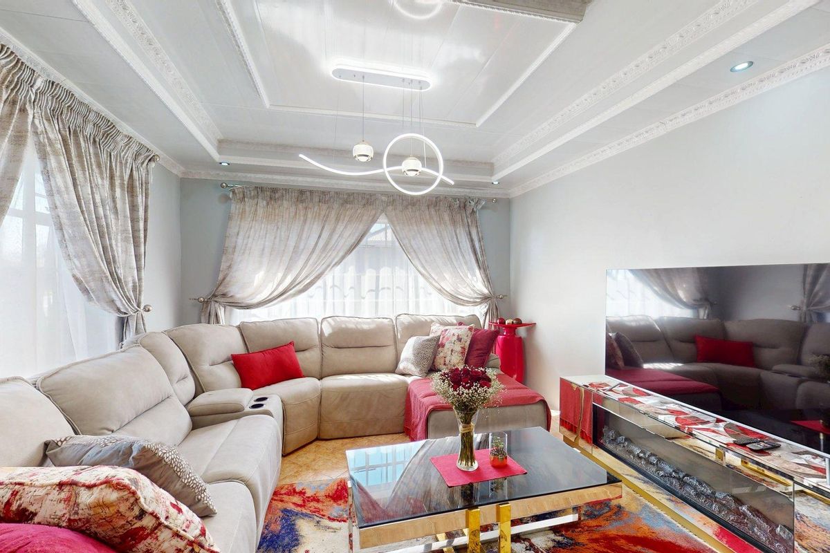 A well-maintained living room featuring a decorative tray ceiling with modern lighting and a built-in electric fireplace.