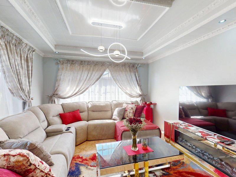 A well-maintained living room featuring a decorative tray ceiling with modern lighting and a built-in electric fireplace.