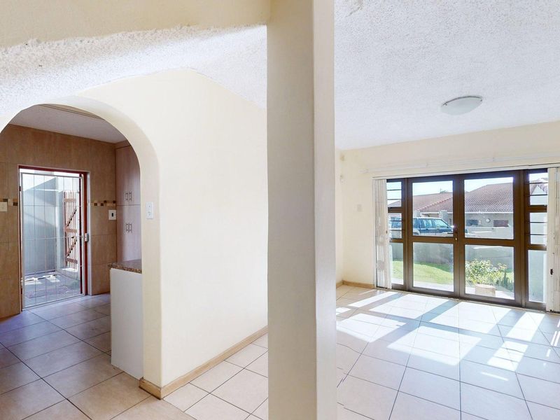 An open-plan living area featuring tiled flooring, a distinctive archway, and sliding glass doors that provide access to the exterior.