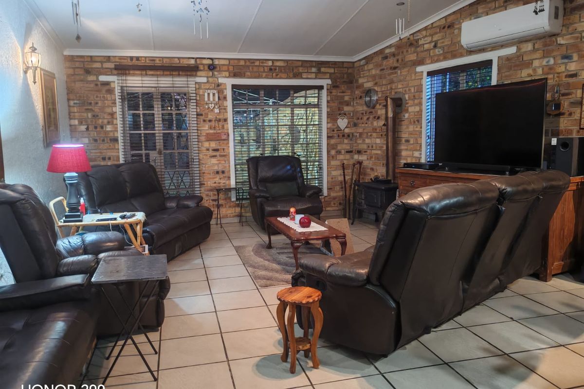 Spacious living room featuring exposed brick walls, tiled flooring, a wood-burning stove, and a wall-mounted air conditioning unit.