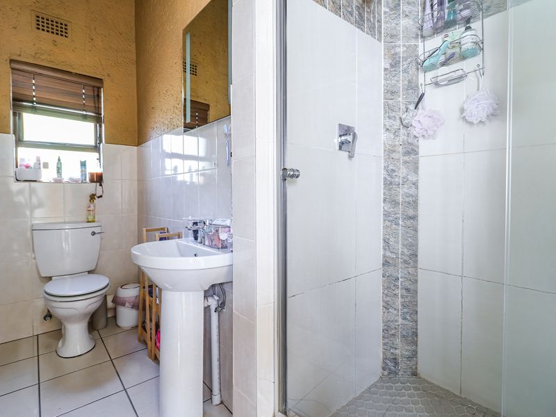A functional bathroom featuring a pedestal basin, toilet, and a separate shower enclosure with tiled finishes throughout.