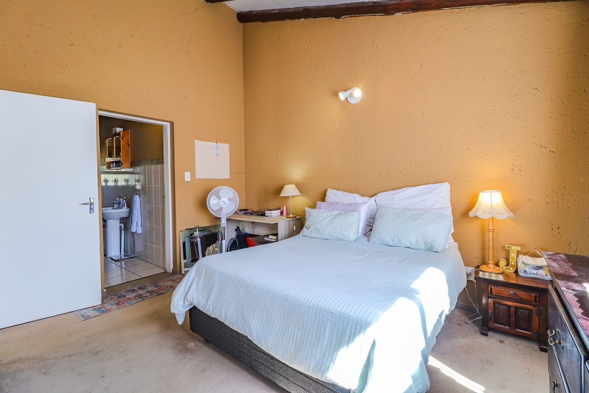 Bedroom featuring an exposed timber ceiling beam and direct access to an en-suite bathroom, requiring cosmetic updates to finishes.
