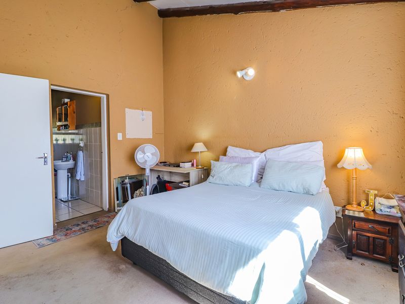 Bedroom featuring an exposed timber ceiling beam and direct access to an en-suite bathroom, requiring cosmetic updates to finishes.