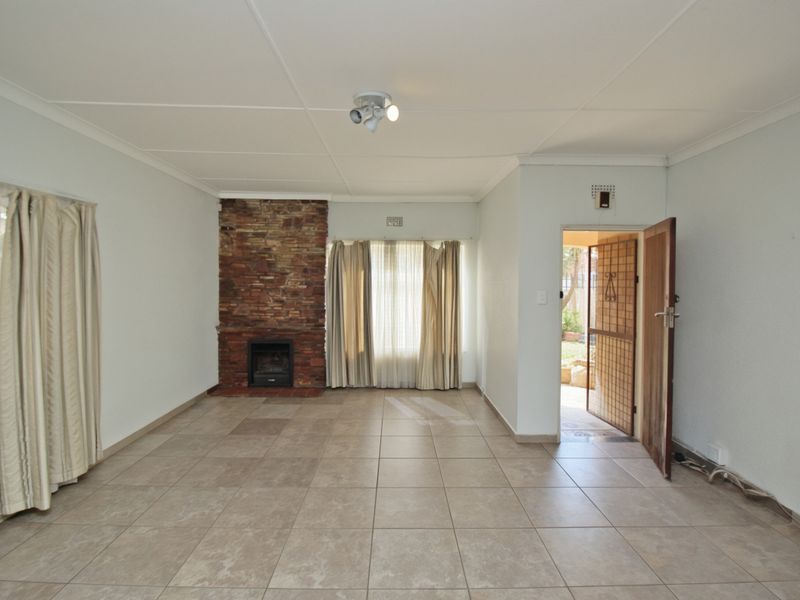 Spacious living room featuring a stone fireplace, tiled flooring, and direct access to the exterior through a security gate.