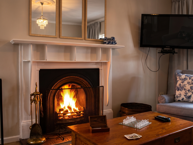 A cozy living room featuring a traditional fireplace with a white mantelpiece and decorative crown molding, creating a warm and inviting atmosphere.