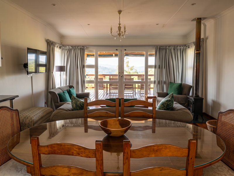 Open-plan living and dining area featuring a wood-burning stove, laminate flooring, and large glass sliding doors opening to an outdoor deck.