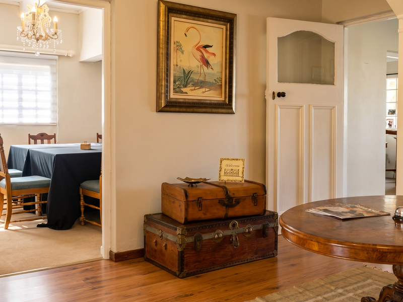 Welcoming entrance hall featuring warm timber flooring, a classic panelled door, and a decorative crystal chandelier, leading into the adjacent dining area.