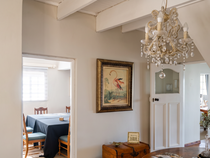 A bright living area featuring exposed timber ceiling beams, a decorative crystal chandelier, and classic panelled interior doors leading to adjacent rooms.