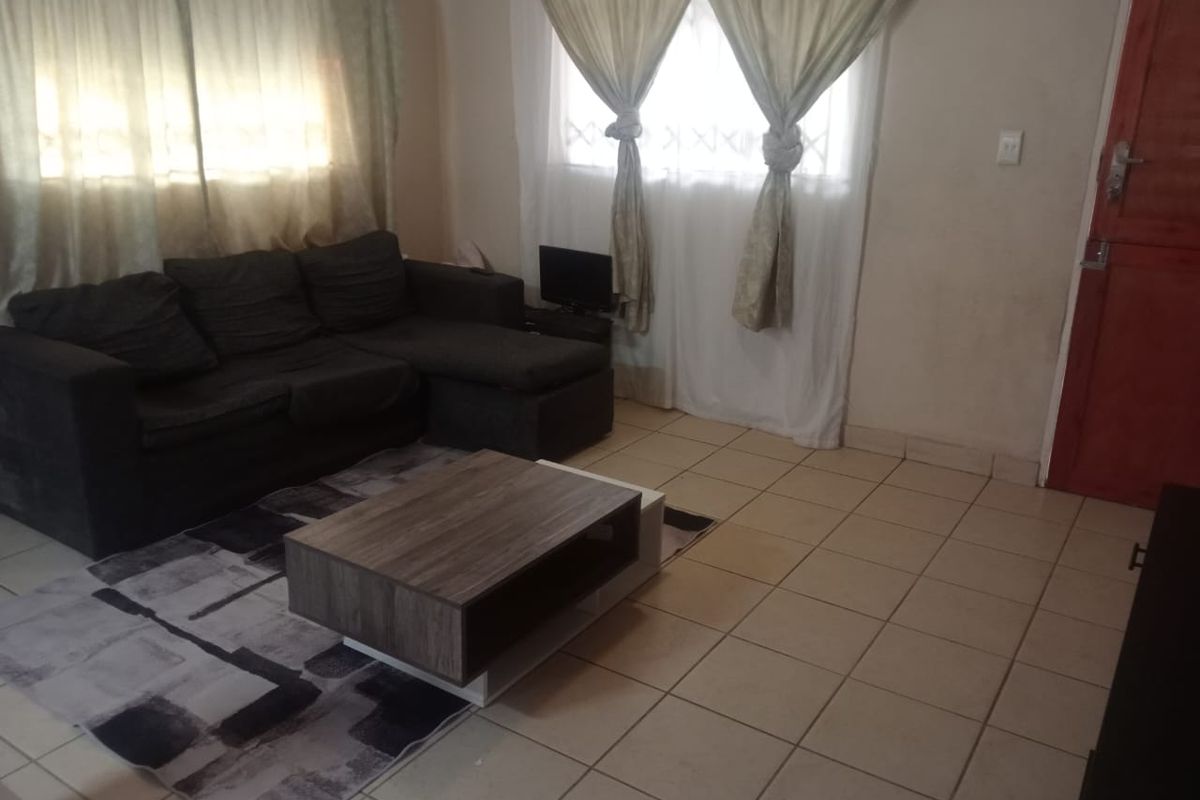 A living room featuring tiled flooring, security bars on the windows, and a timber entrance door.