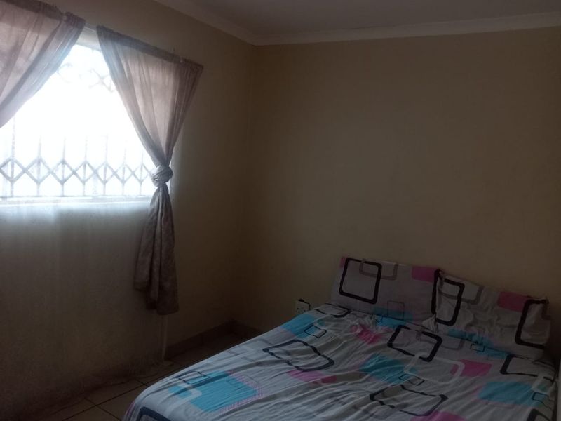 A standard bedroom featuring tiled flooring, a window with security bars, and neutral wall finishes.